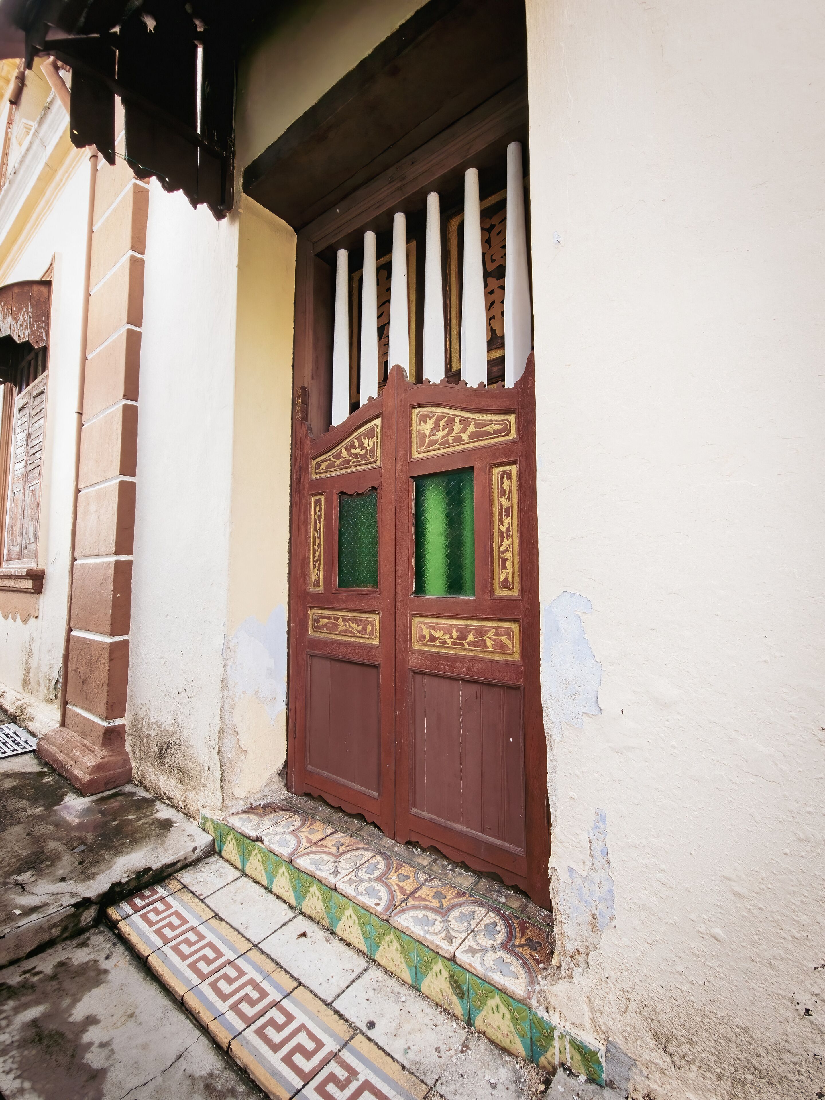 A traditional wooden door with decorative panels and a tiled entrance step.