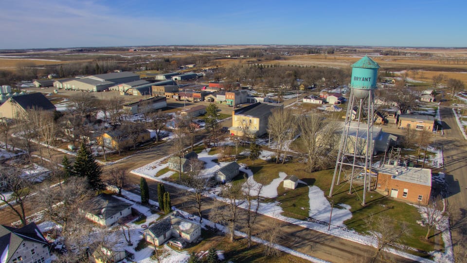 A town with a prominent water tower labeled "BRYANT" amidst residential houses and industrial buildings.