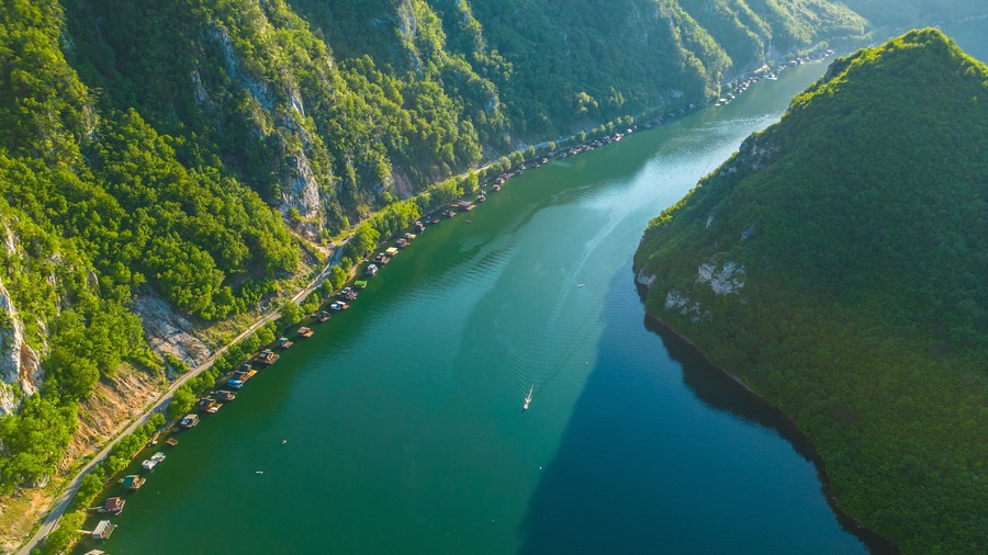 Un río serpentea a través de un paisaje montañoso con densos bosques a ambos lados.