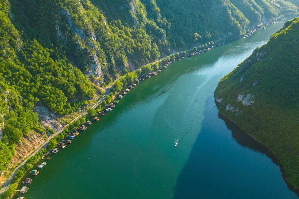 Ein Fluss schlängelt sich durch eine gebirgige Landschaft, gesäumt von dichten Wäldern.