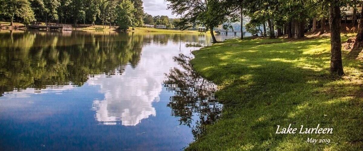 A calm lake with reflections of trees and a clear sky.