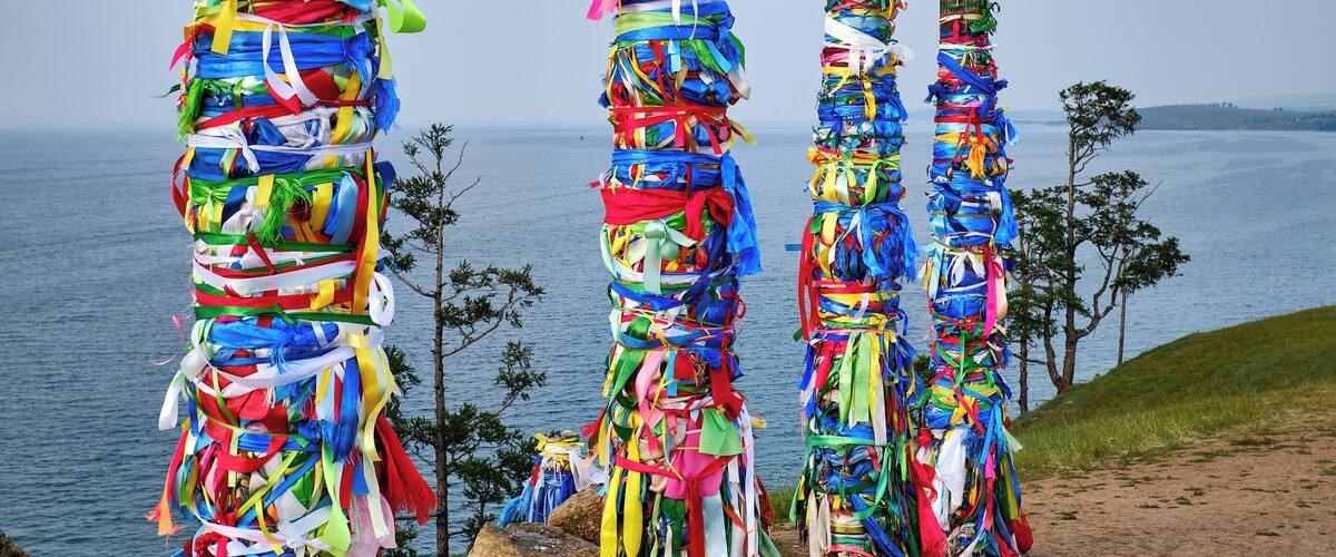 #Adventure Contest
Sacred shaman poles on Olkhon Island, called the heart of Lake Baikal.
The Shaman Rock is one of the nine most holy places in Asia. 13 totem poles stand tall at the entrance, guarding the sacred rock, representing the 13 deities of Olkhon and bearing colorful ribbons, known as ‘Khadag’, placed by pilgrims. The five colors symbolize different aspects of the environment. Blue for the eternal sky, green for the earth, yellow for religion, red for fire, white for milk.