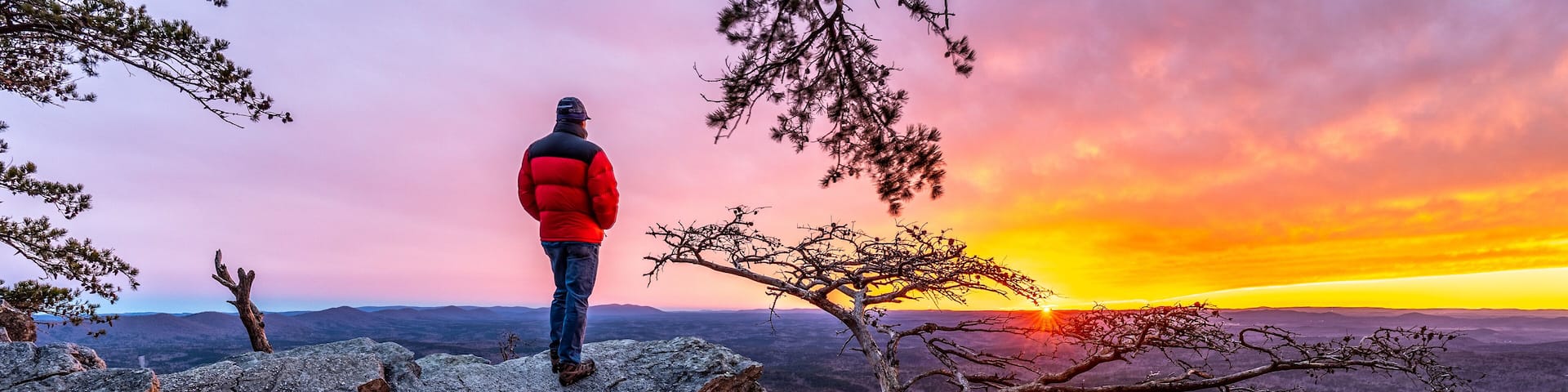 Man, person, standing on a rock high above a valley watching the sun setting in the distance, Pulpit Rock, Cheaha State Park, Alabama
