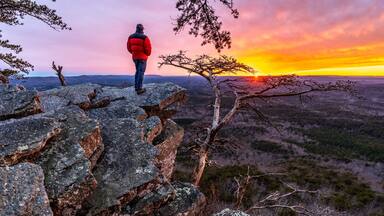 Man, person, standing on a rock high above a valley watching the sun setting in the distance, Pulpit Rock, Cheaha State Park, Alabama