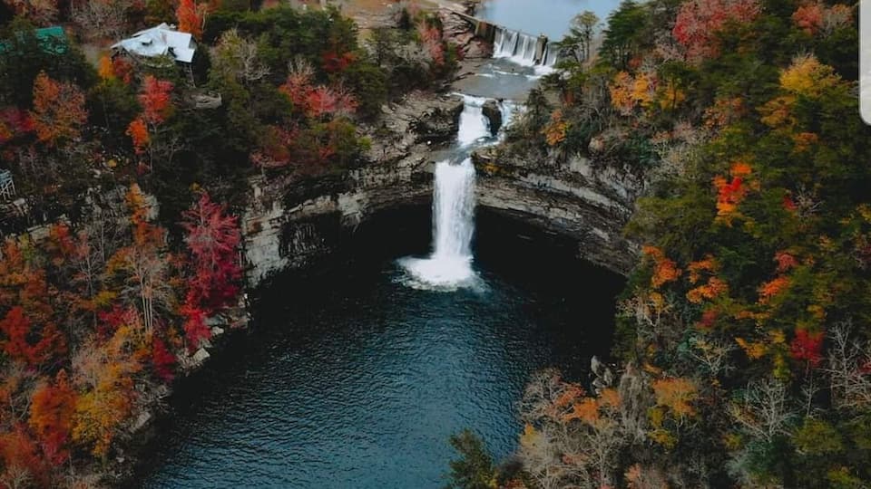 A waterfall surrounded by autumn-colored trees.