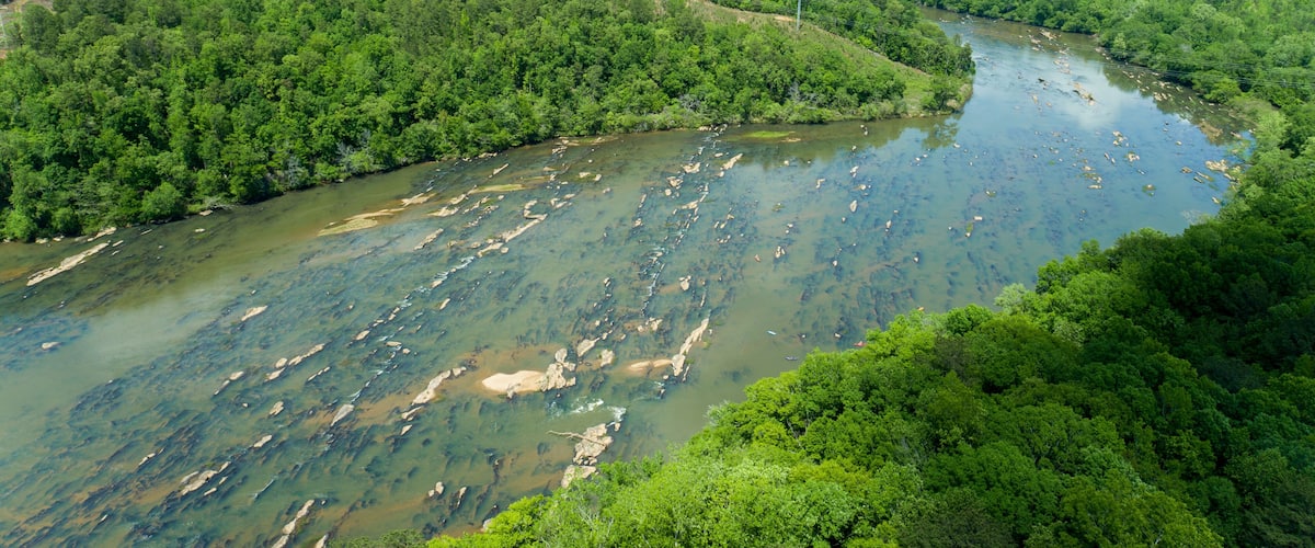 A river winding through a dense forest with visible power lines and a clear waterway.