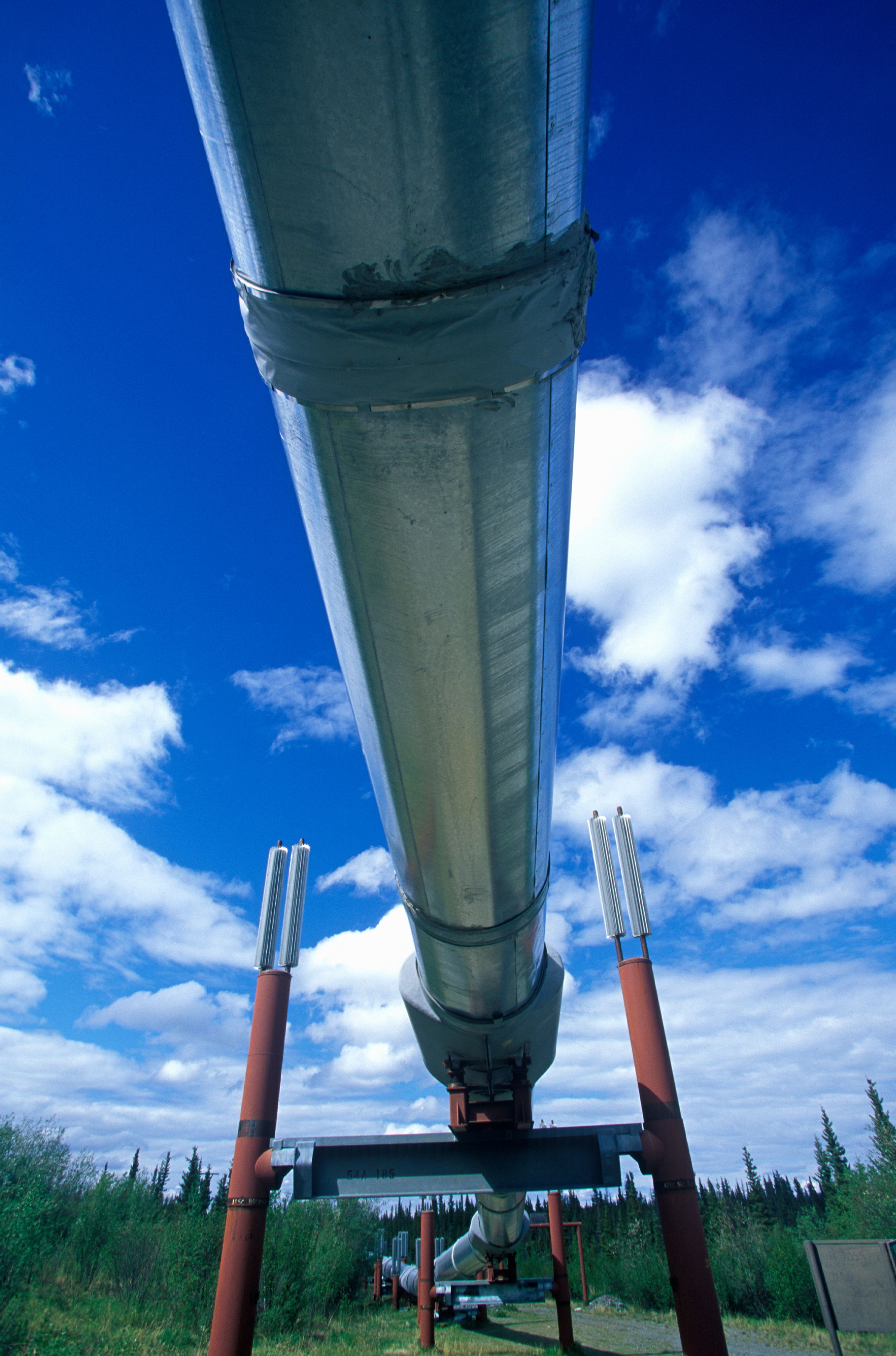 A large industrial funnel structure with a metal roof, supported by red metal legs, set against a clear blue sky with scattered clouds.