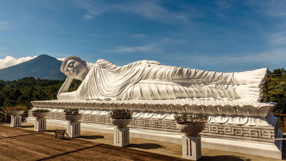 A large reclining Buddha statue with a mountainous backdrop.