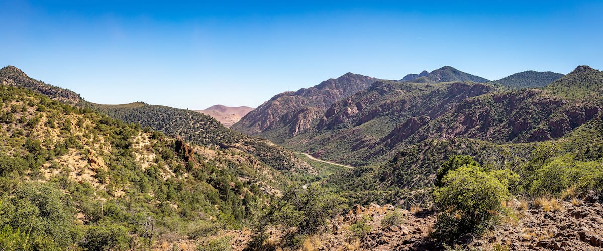 A mountainous landscape with a winding road through a valley.