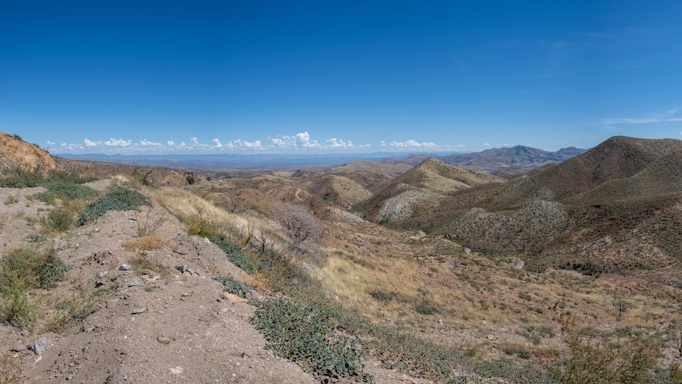 A rugged mountainous landscape with sparse vegetation and a clear blue sky.