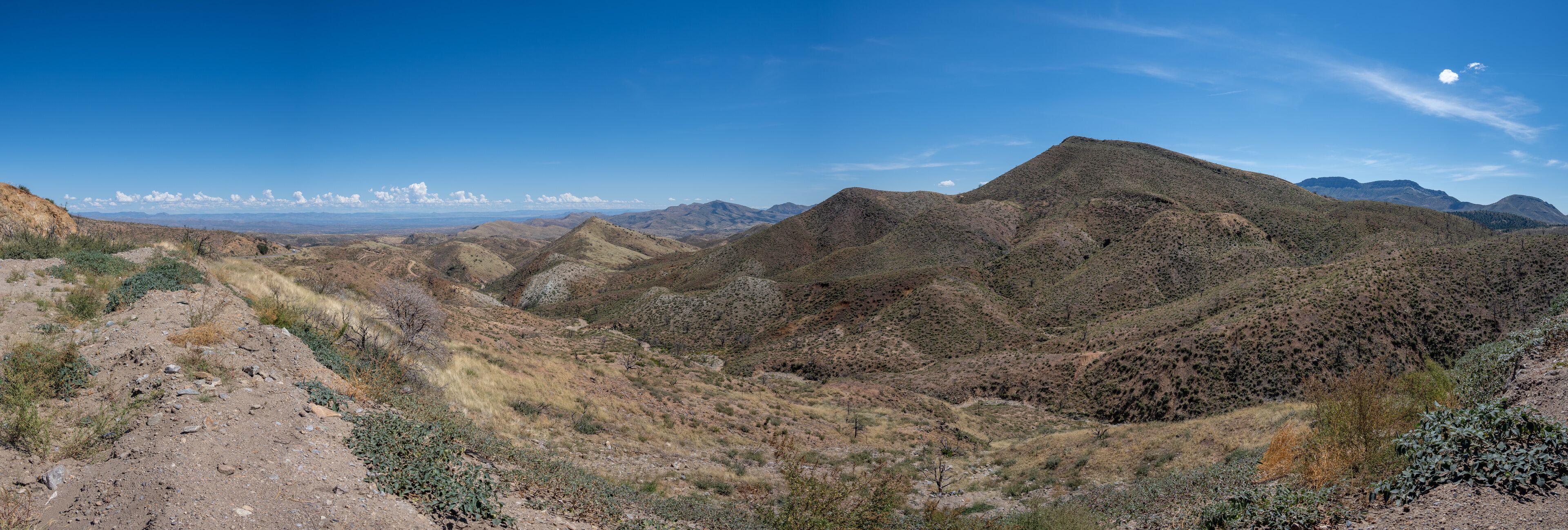 A rugged mountainous landscape with sparse vegetation and a clear blue sky.