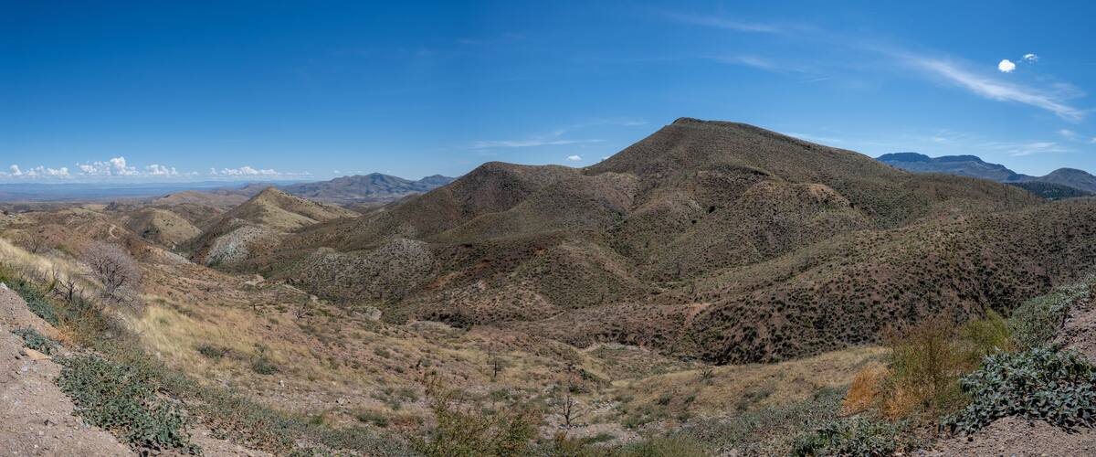A rugged mountainous landscape with sparse vegetation and a clear blue sky.