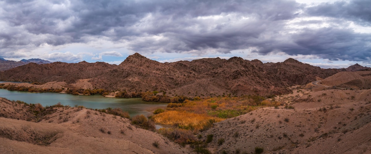 A rugged mountain landscape with a lake and a winding road.