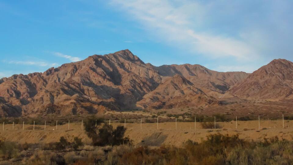 A mountain range with sparse vegetation and a clear sky.