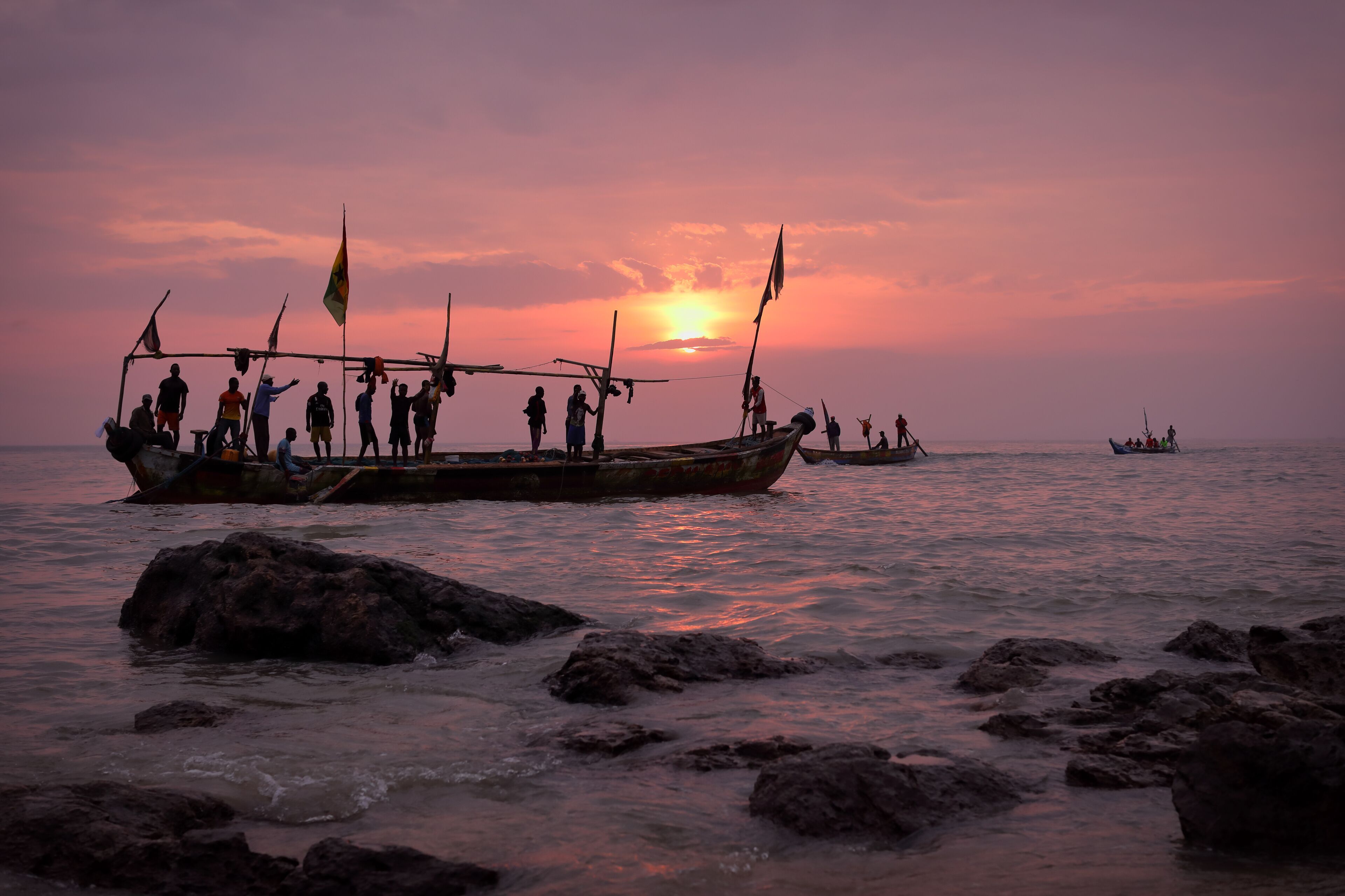A sunset over a body of water with boats and people on a dock.