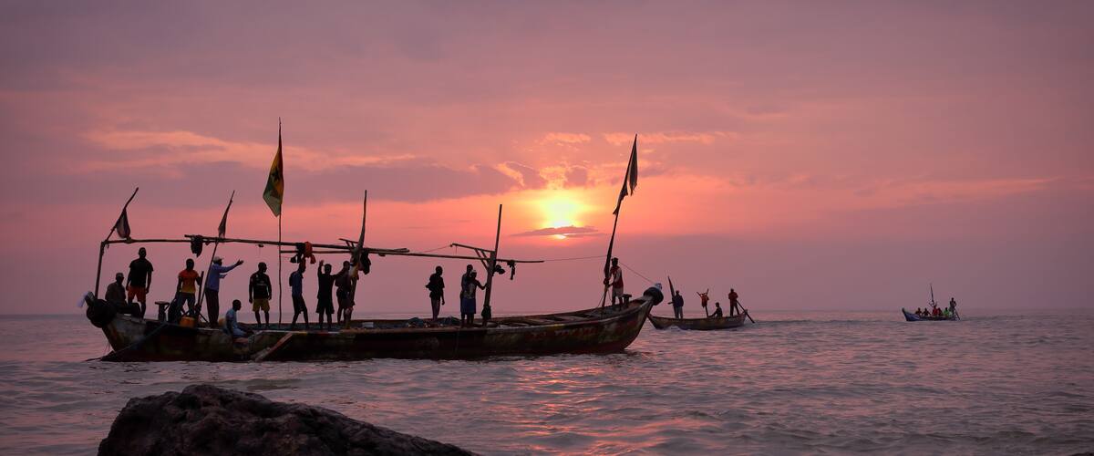 A sunset over a body of water with boats and people on a dock.
