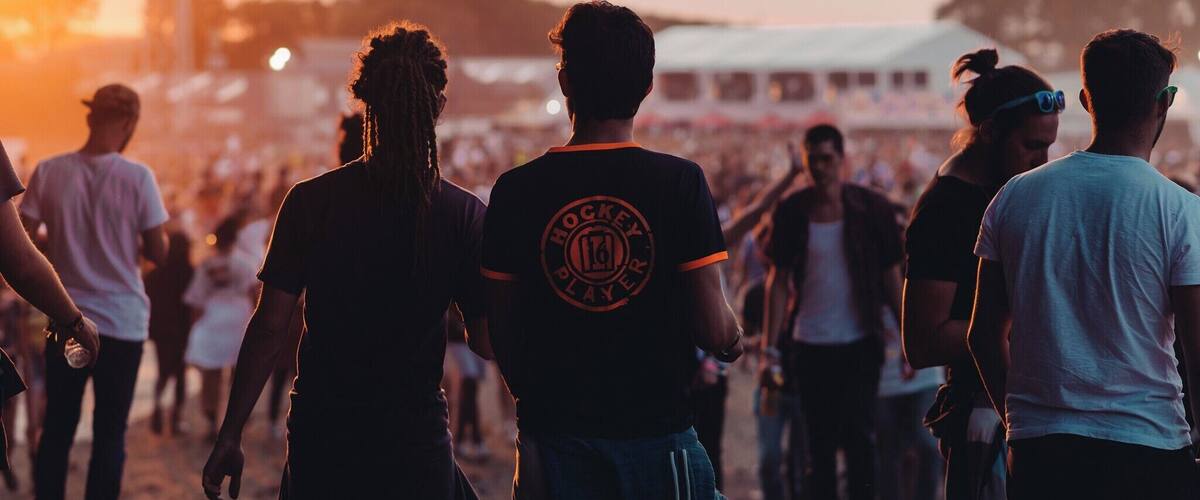 A crowd at a festival with a sunset in the background.