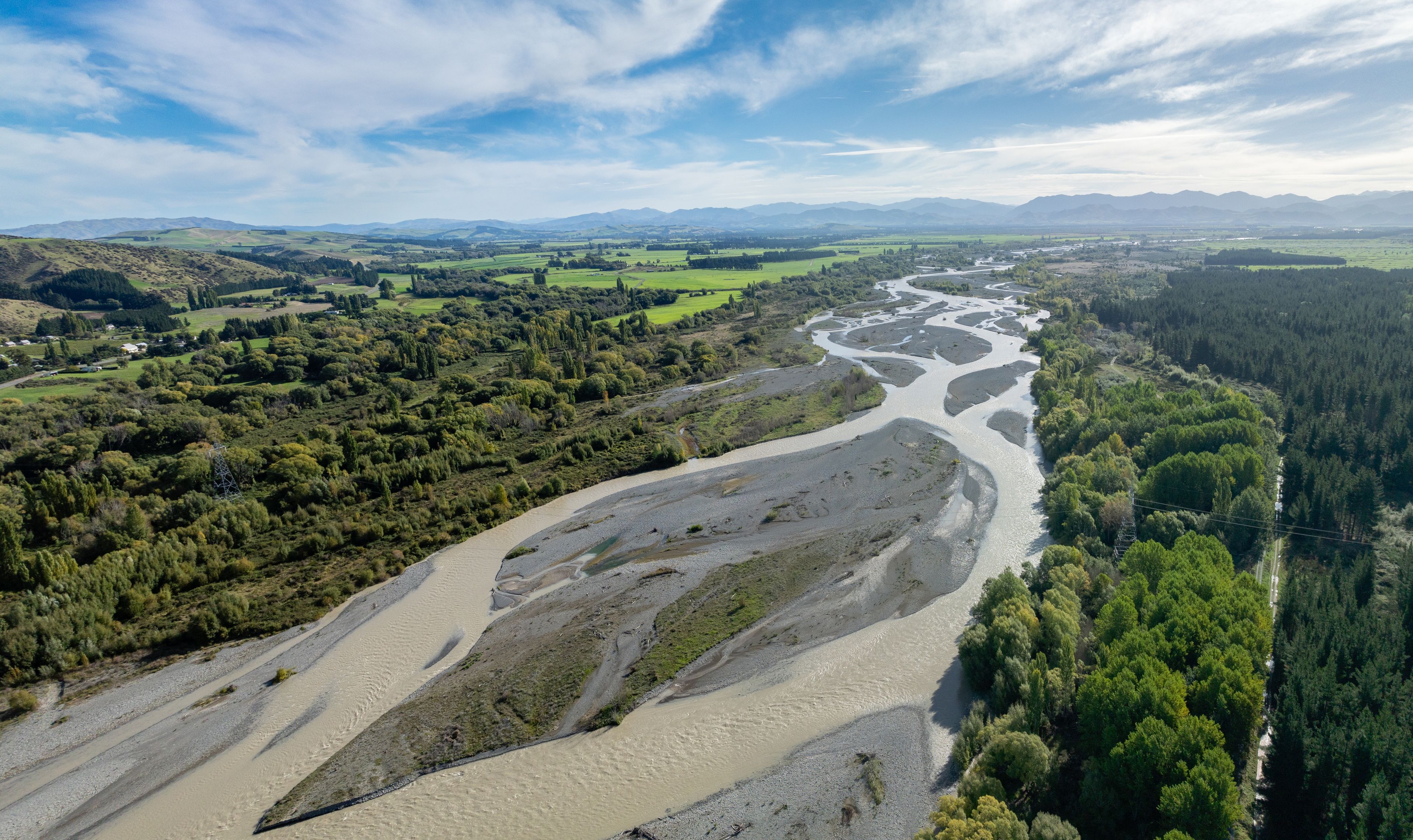 Un río serpentea por un valle rodeado de colinas y bosques.