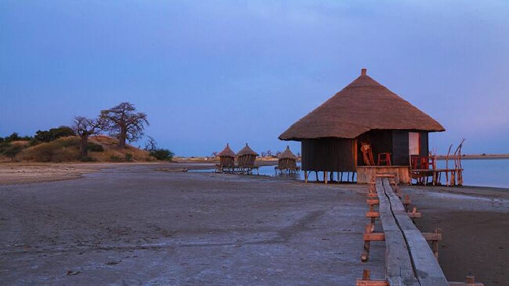 A beach with thatched-roof huts and wooden walkways.