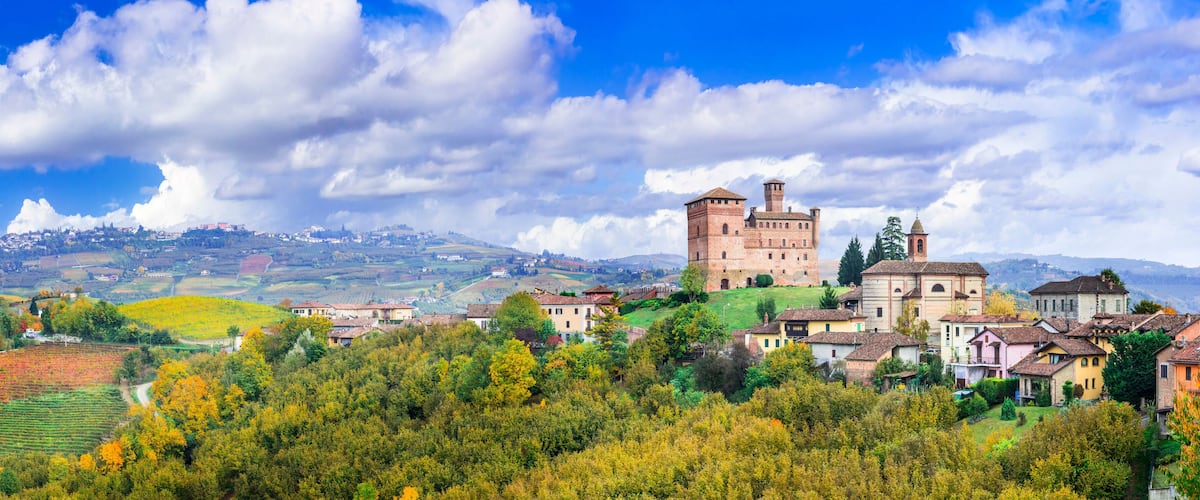 A historic castle on a hill, surrounded by colorful autumn trees and traditional houses.