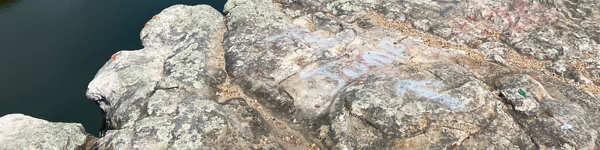 Une rivière serpente à travers une vallée boisée, avec une formation rocheuse en relief au premier plan.