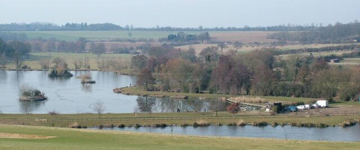 A river with islands, a grassy field, and a distant building.