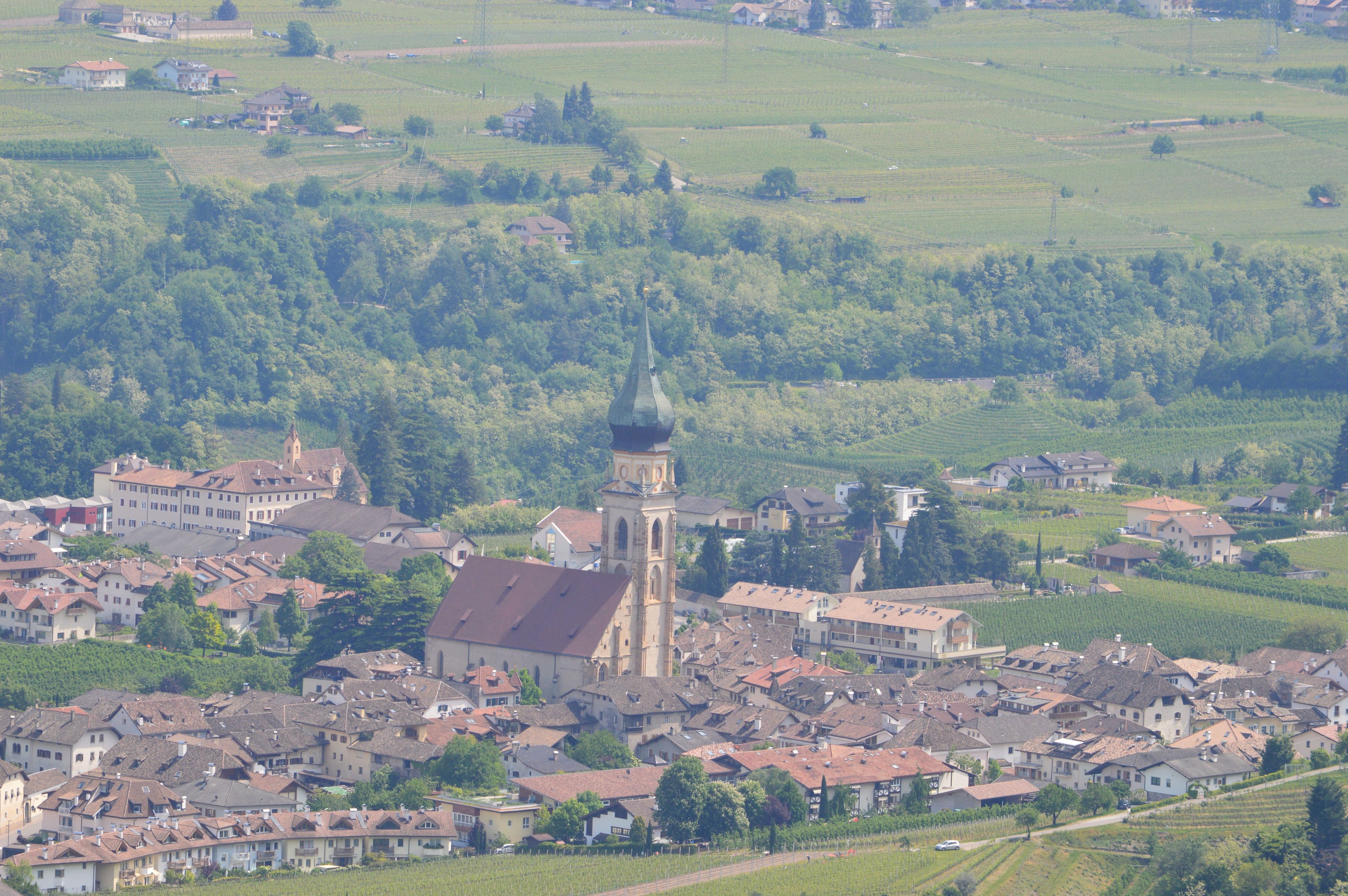 Une ville dont l’église, reconnaissable à son imposant clocher, est entourée de vignobles et d’immeubles d’habitation.
