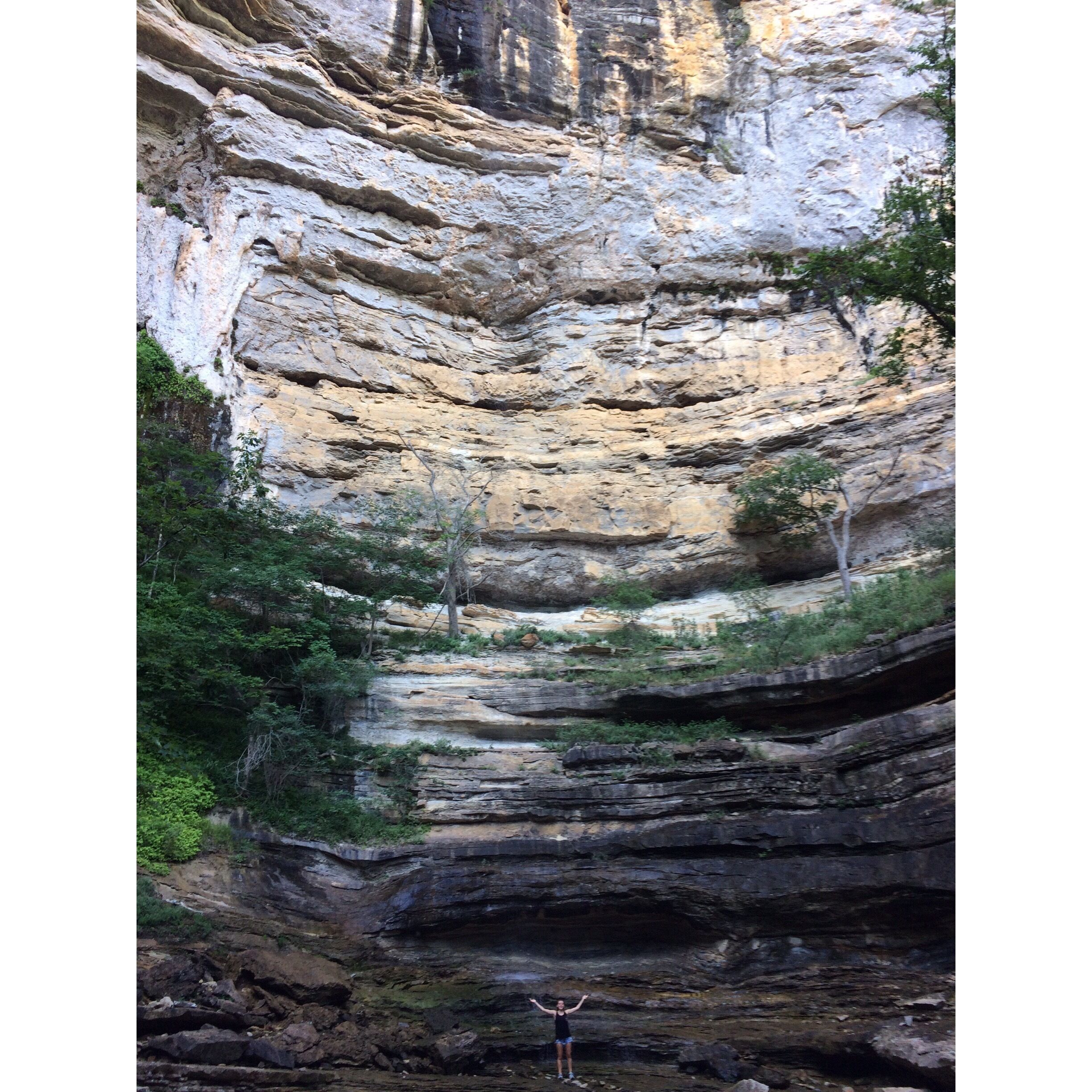 A layered rock formation with a person standing at the bottom.