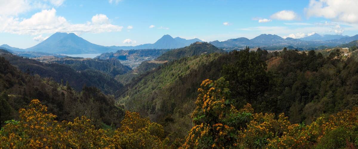 A mountainous landscape with a valley, a lake, and distant mountains.