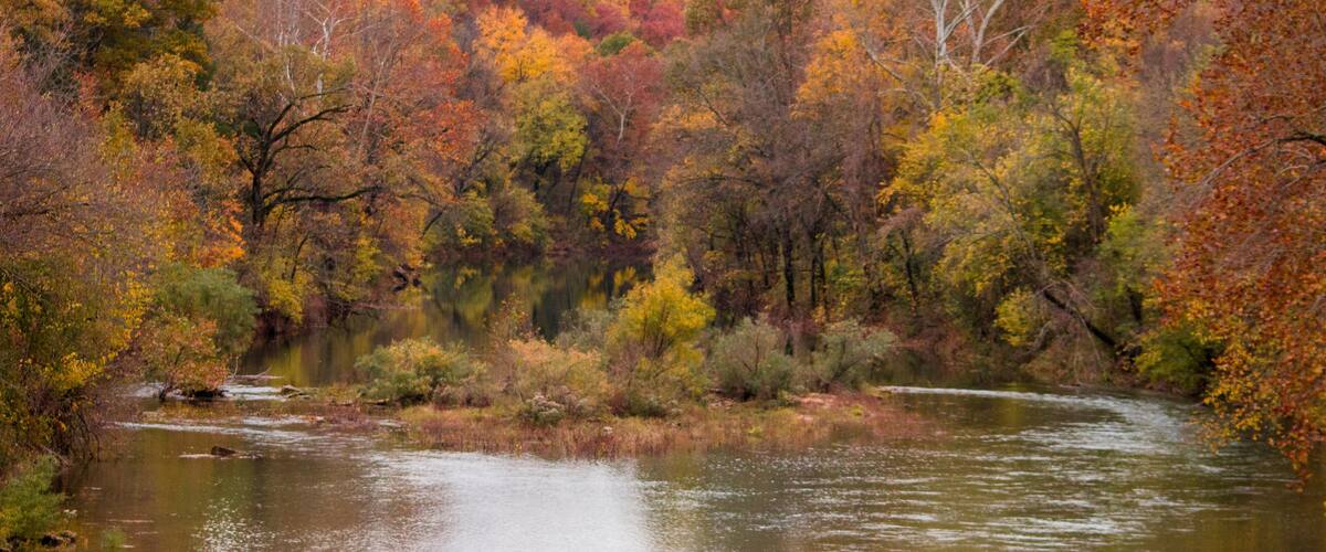 A river surrounded by autumn-colored trees.