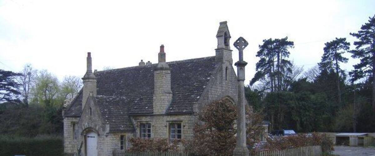 A stone building with a traditional design, a circular driveway, and a memorial with a wreath.