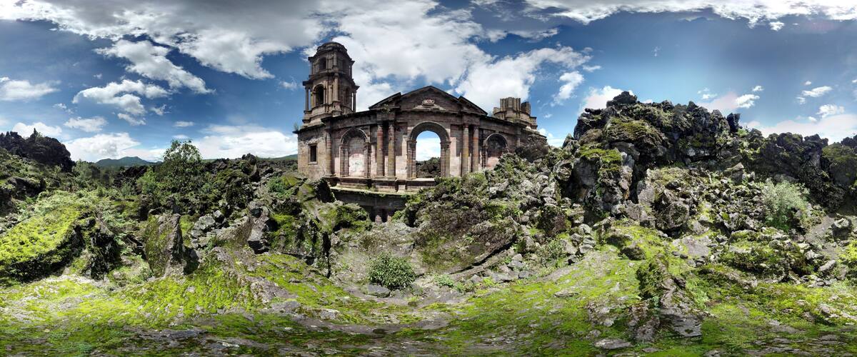 An ancient stone church with a bell tower, surrounded by rocky terrain and greenery.