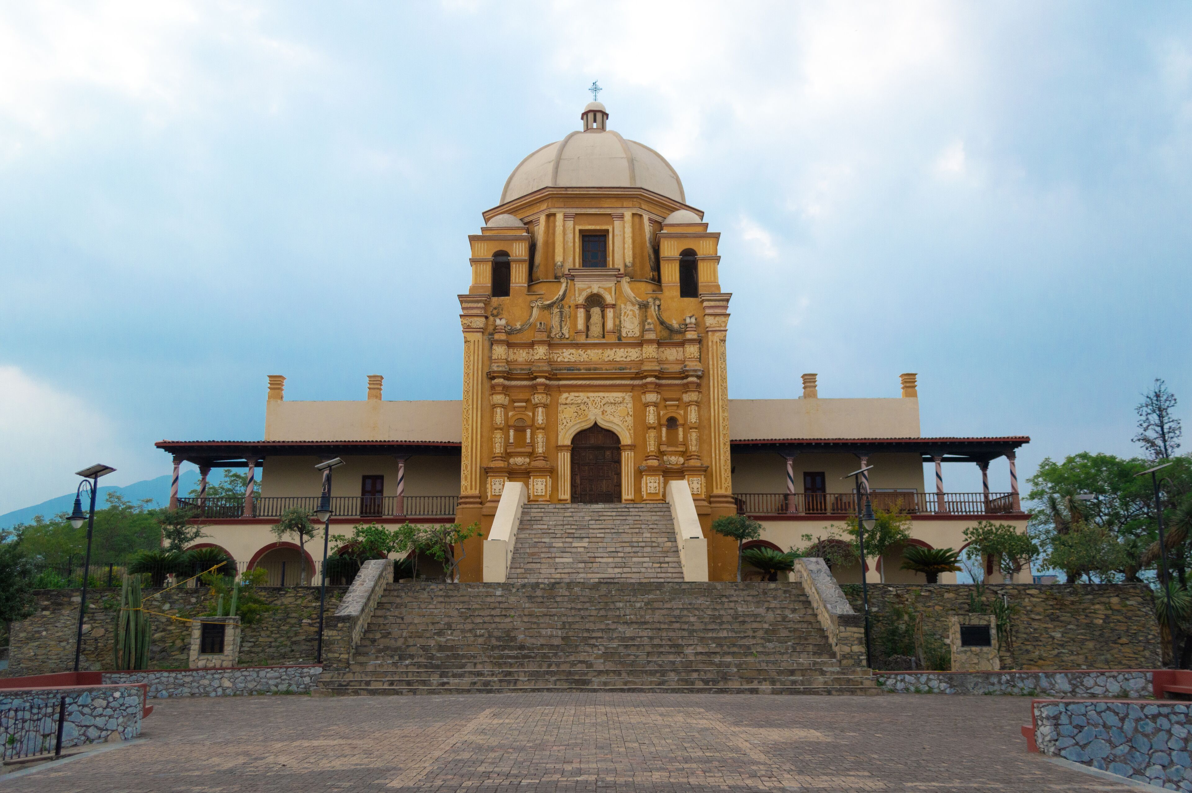 A historic church with a dome and bell towers, surrounded by stone steps and greenery.
