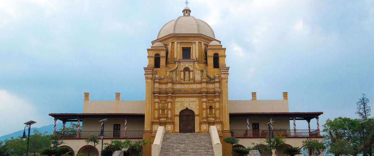 A historic church with a dome and bell towers, surrounded by stone steps and greenery.