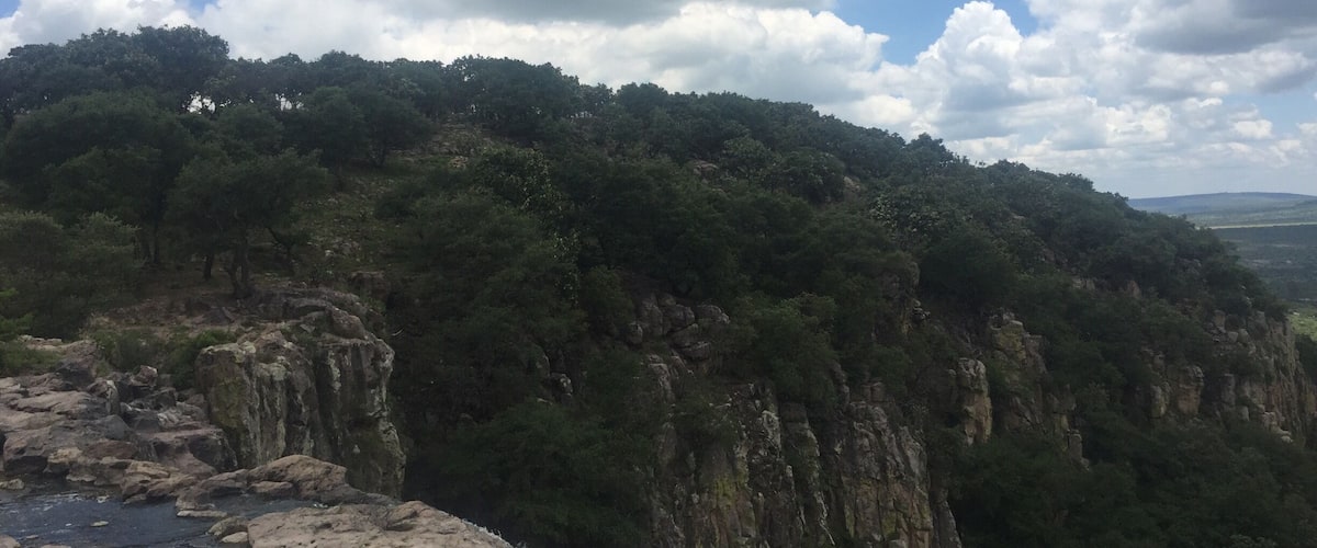 A mountainous landscape with dense green forests and rocky cliffs.