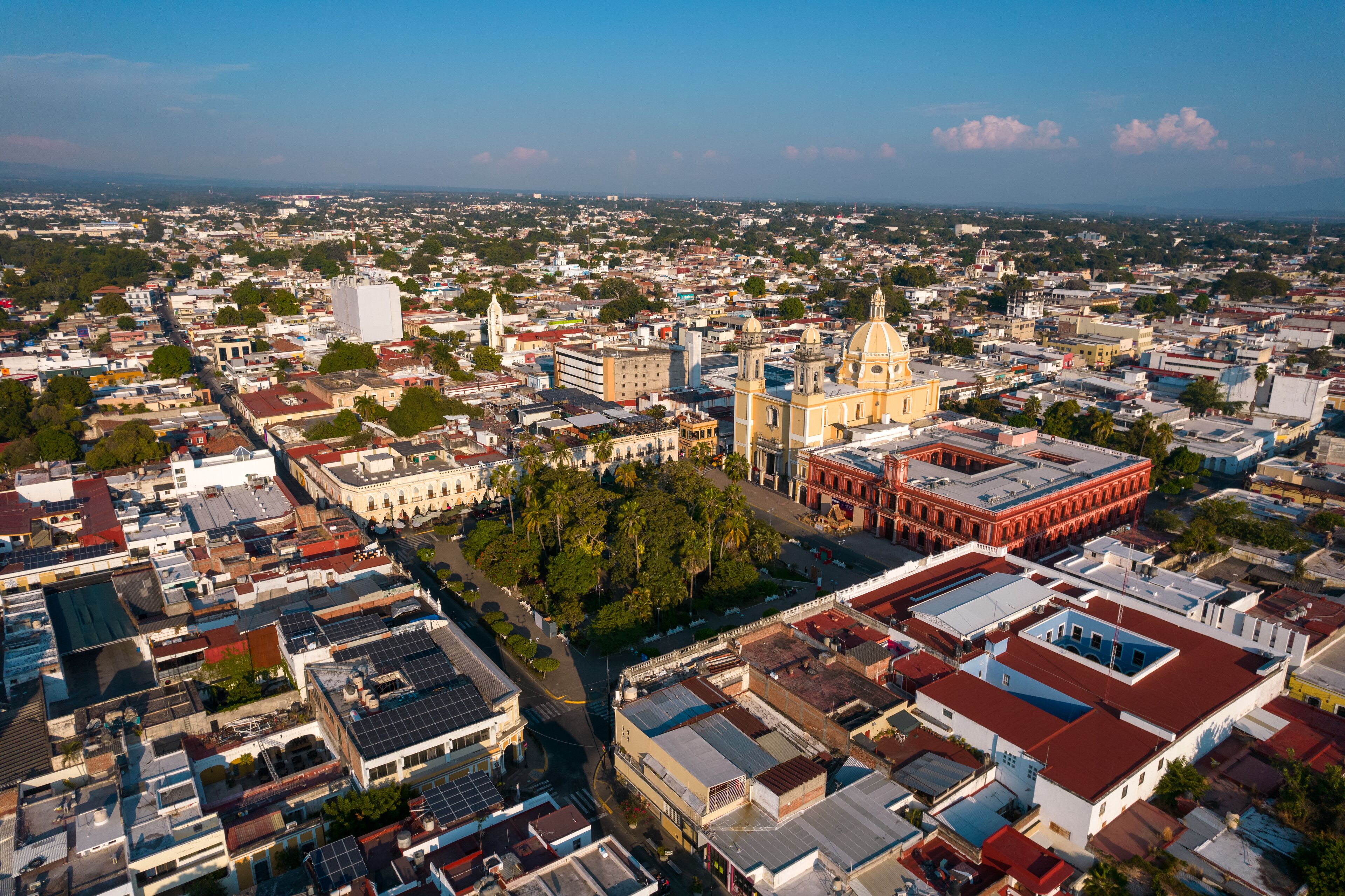 An aerial view of a city with a prominent cathedral, dense urban buildings, and a clear sky.