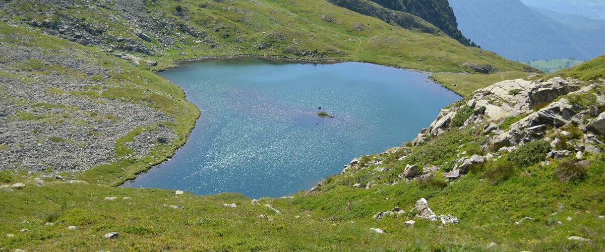 A mountain lake surrounded by green hills and rocky terrain.