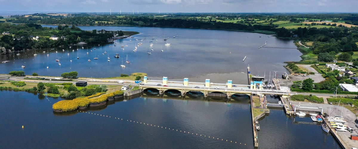 A river with boats, a bridge, and surrounding greenery.