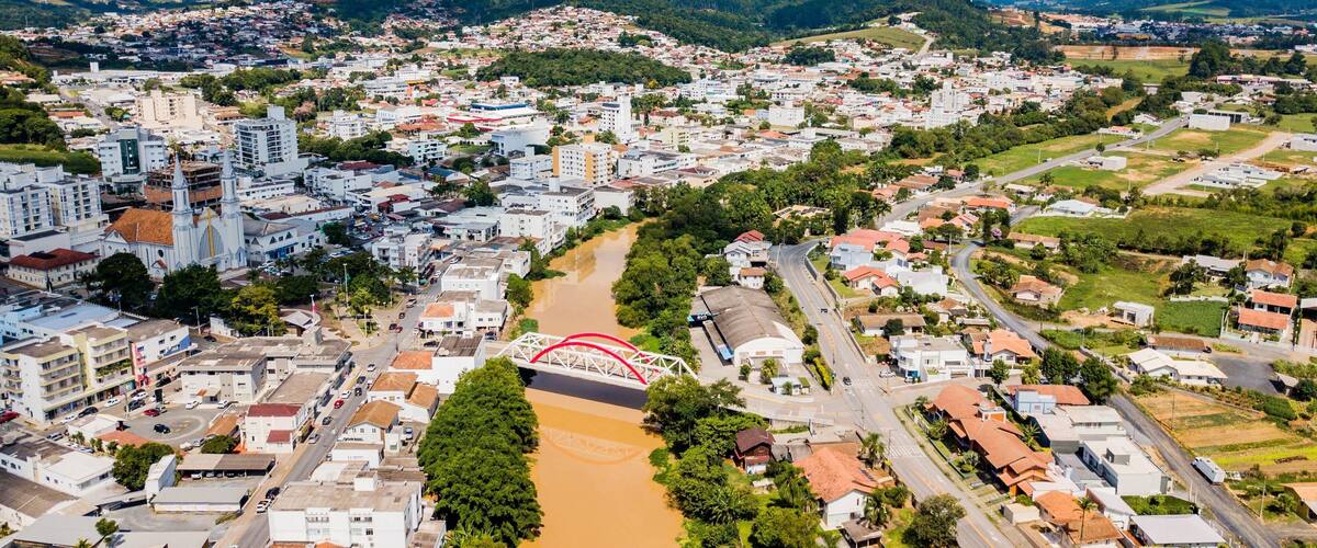 An aerial view of a city with a river, a prominent church, and surrounding hills.