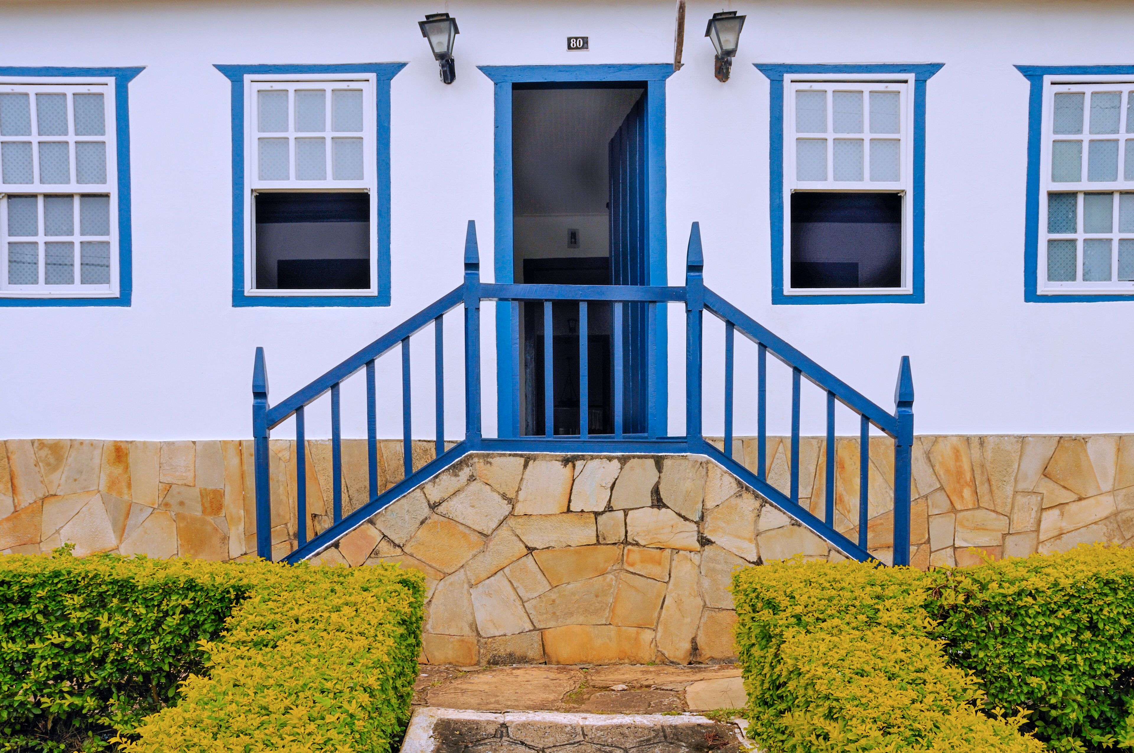 A white building with blue trim and a stone staircase leading to a door.