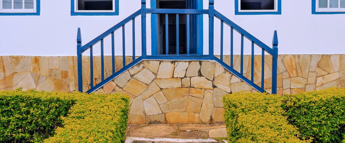 A white building with blue trim and a stone staircase leading to a door.