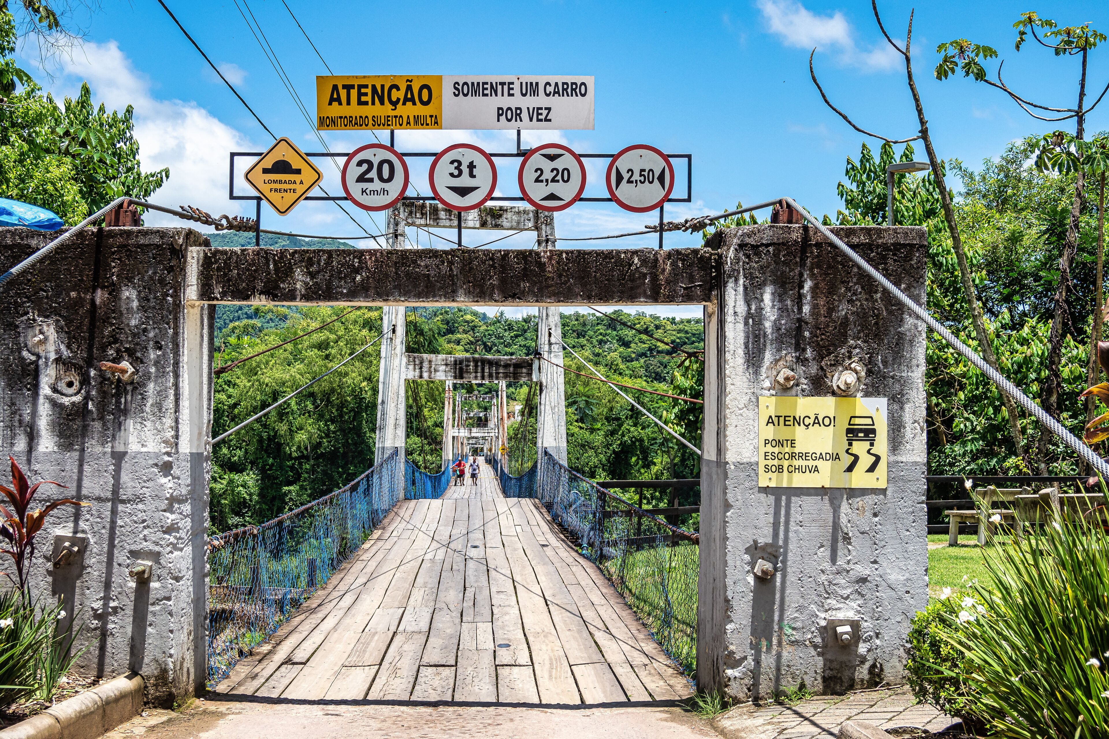 A wooden bridge with signs indicating speed limits and a warning for a car passing once.