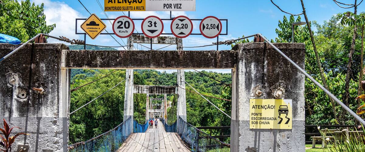 A wooden bridge with signs indicating speed limits and a warning for a car passing once.