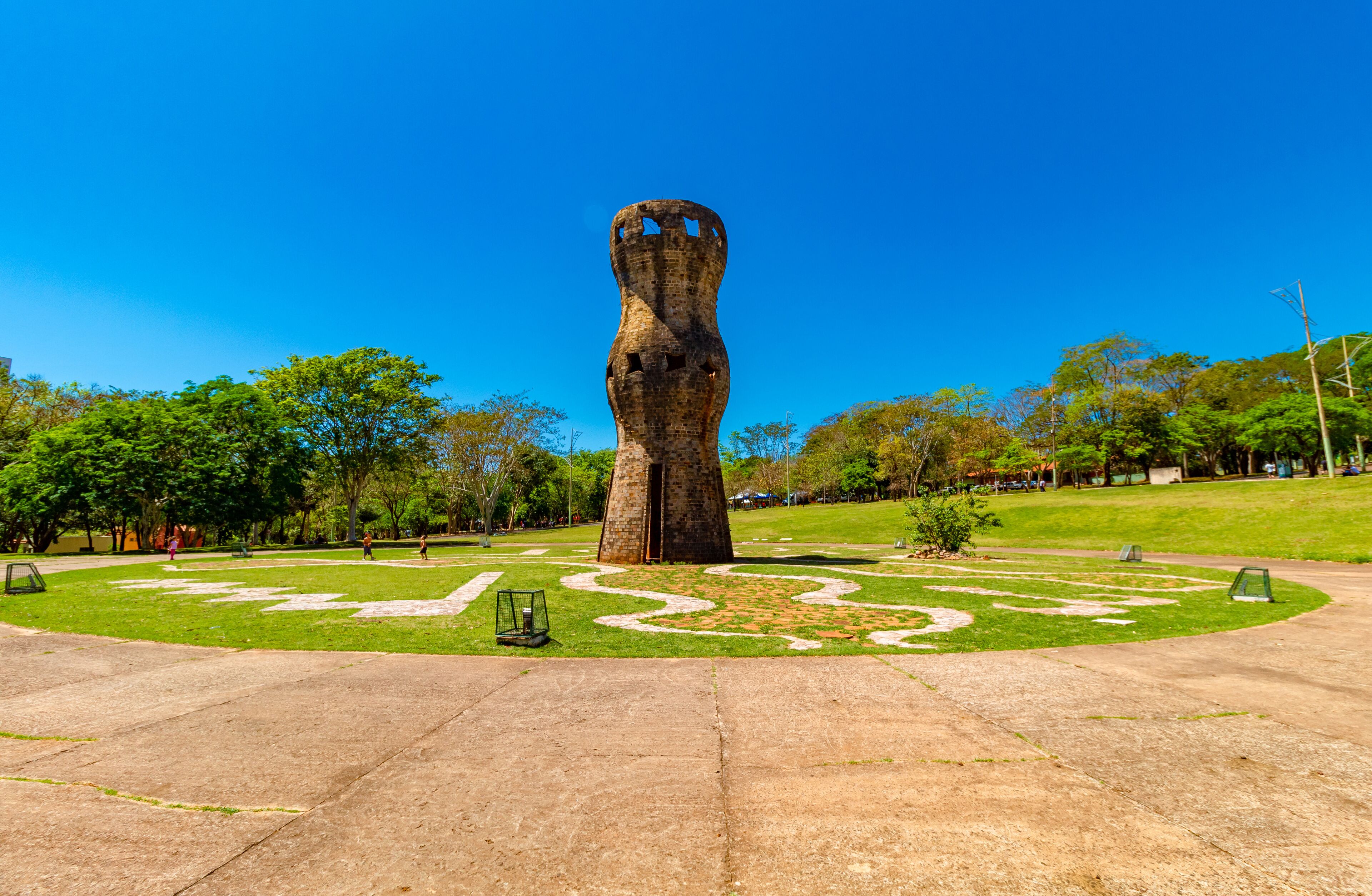 A large, abstract sculpture in a park with a clear blue sky.