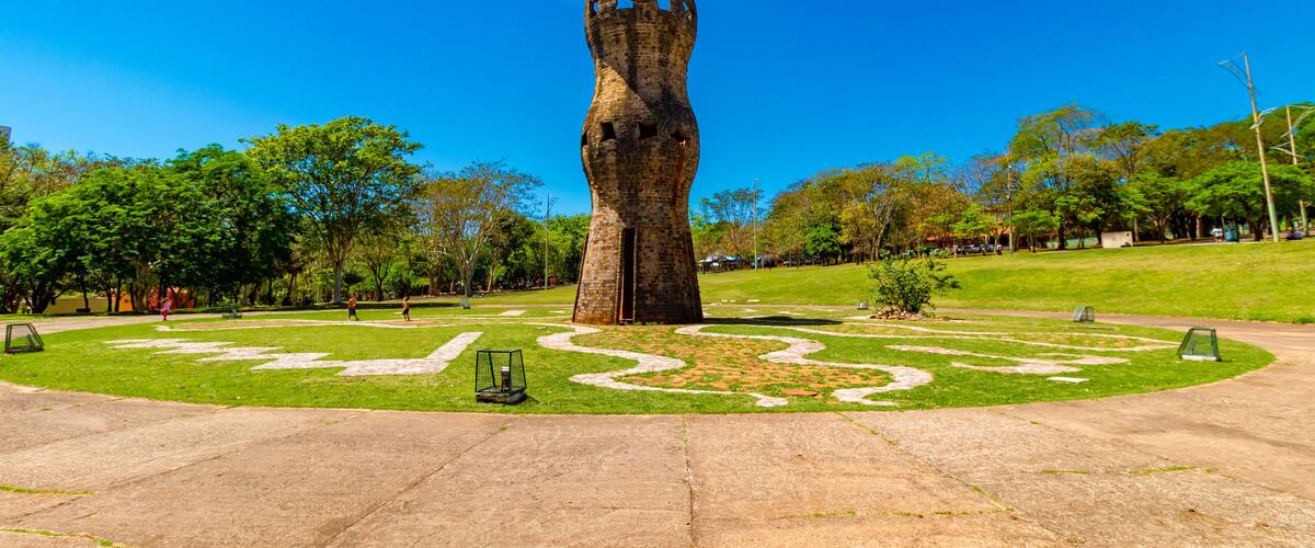 A large, abstract sculpture in a park with a clear blue sky.