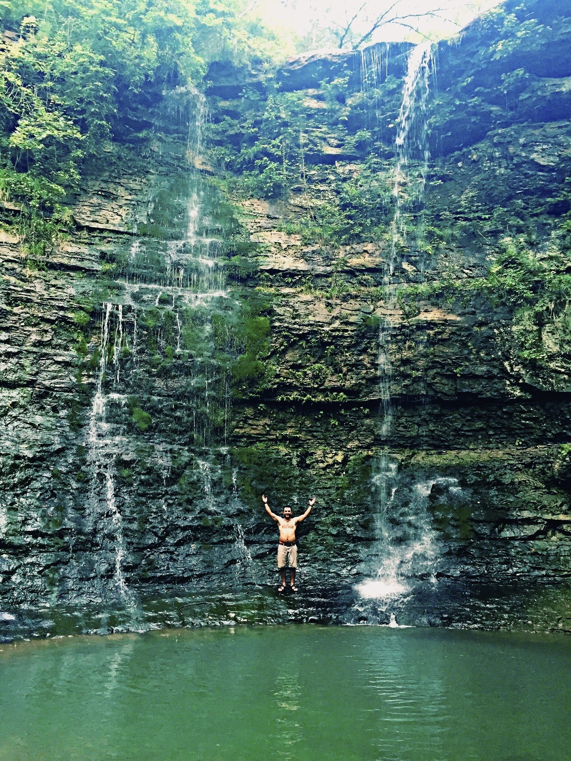 A waterfall with a person standing in the water.
