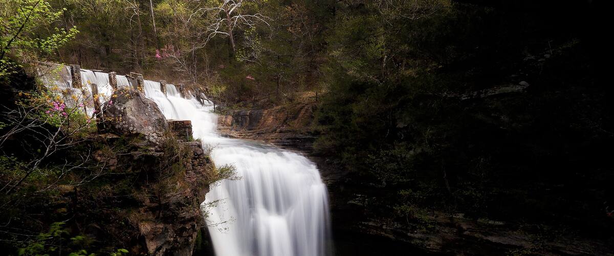 A waterfall cascading down a rocky cliff surrounded by dense forest.