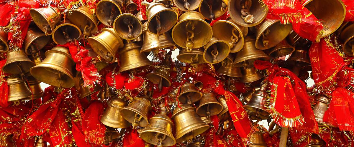 A collection of brass bells and red ribbons.