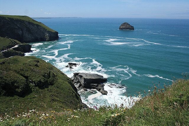 Un paisaje costero con acantilados rocosos, una pequeña isla y el océano.