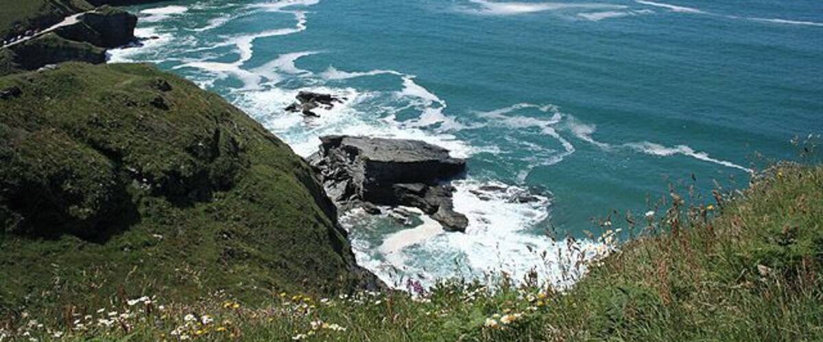 A coastal landscape with rocky cliffs, a small island, and the ocean.